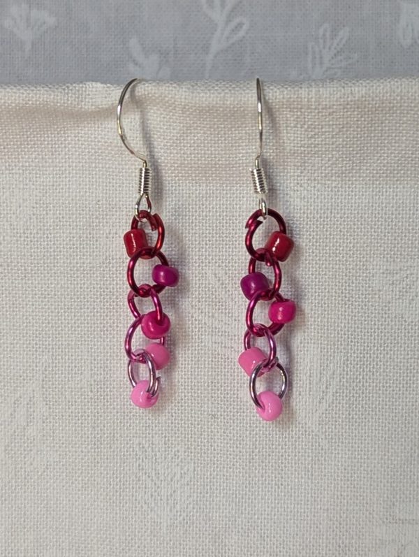 Handmade Rosy Rhapsody Earrings with five pink and red beads linked to red-to-pink gradient jump rings and sterling silver hooks.