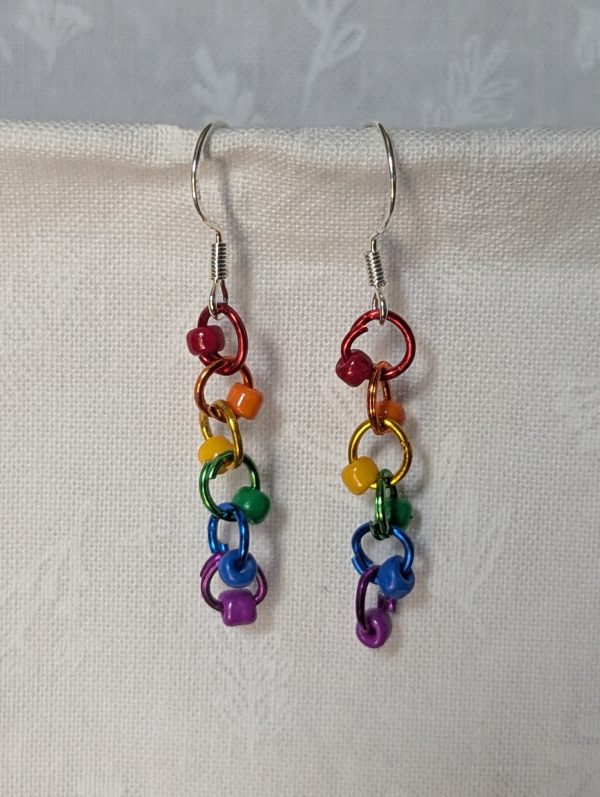 Colorful handmade Rainbow Whimsy Earrings with five bright beads on rainbow gradient jump rings and sterling silver hooks.