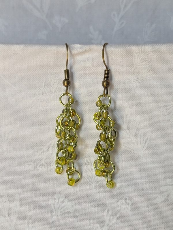 Handmade lime green earrings with 18 assorted green glass beads, lime green jump rings, and antique bronze-colored hooks.