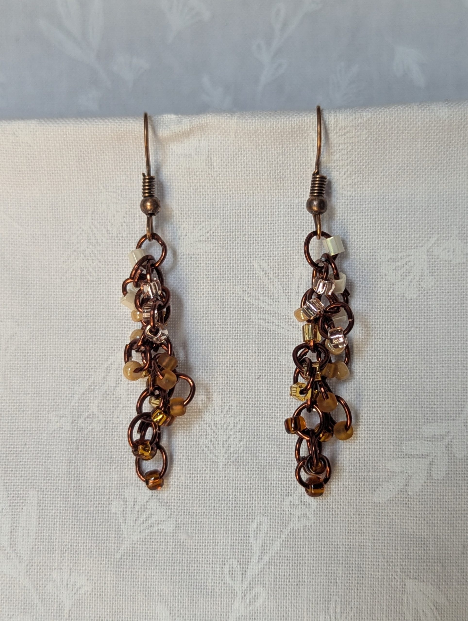 Handmade earrings with 21 gradient cream-to-brown beads on brown jump rings and antique bronze hooks.
