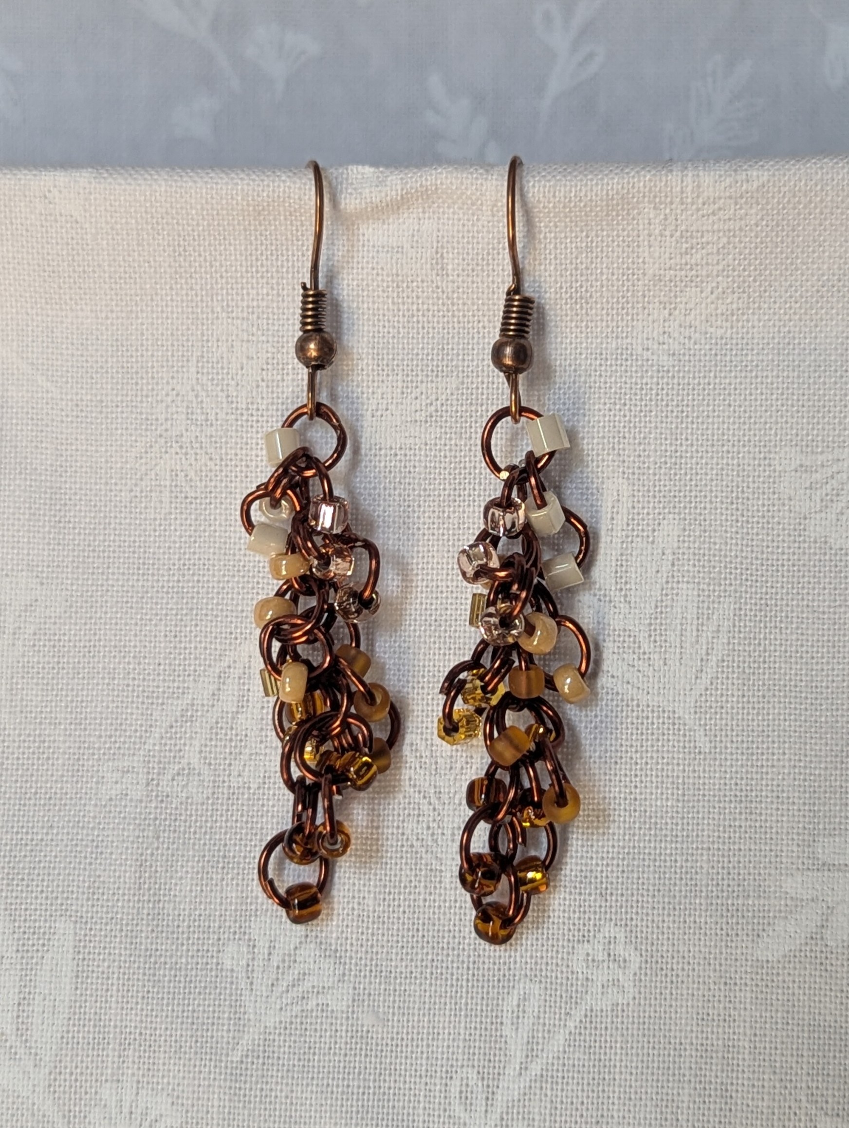 Handmade earrings with 21 gradient cream-to-brown beads on brown jump rings and antique bronze hooks.