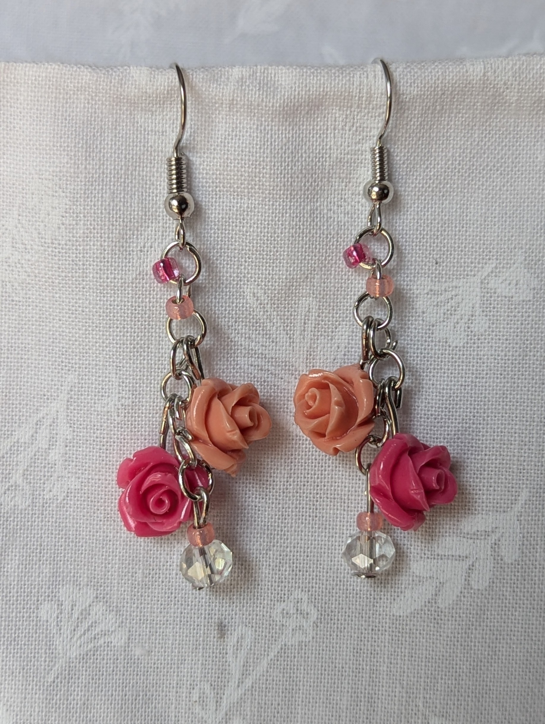 Handmade blush rose cascade earrings with coral and pink roses, glass seed beads, and crystal accents on steel colored hooks.