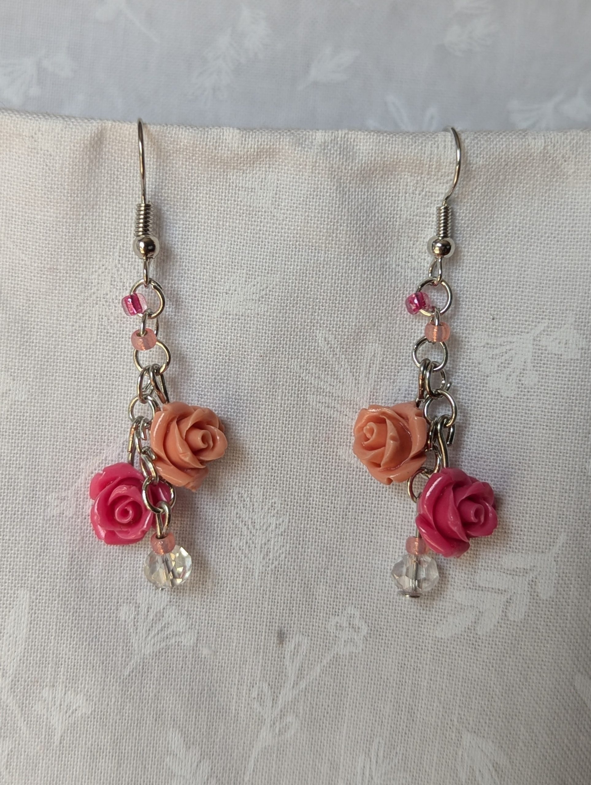 Handmade blush rose cascade earrings with coral and pink roses, glass seed beads, and crystal accents on steel colored hooks.