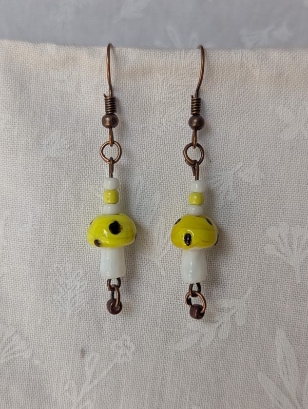 Handmade yellow mushroom earrings with glass toadstools, yellow, brown and white seed beads, and bronze colored hooks.