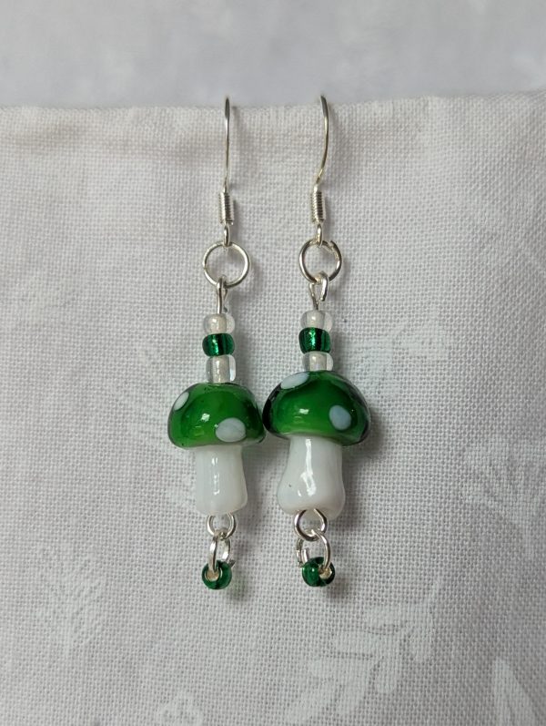 Handmade green mushroom earrings with glass toadstools, green and white seed beads, and sterling silver hooks.