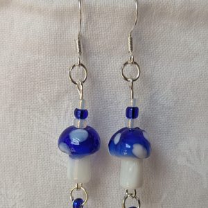 Handmade blue mushroom earrings with glass toadstools, blue and white seed beads, and sterling silver hooks.