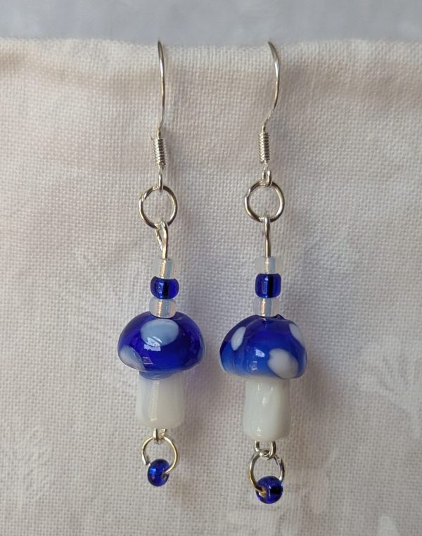 Handmade blue mushroom earrings with glass toadstools, blue and white seed beads, and sterling silver hooks.