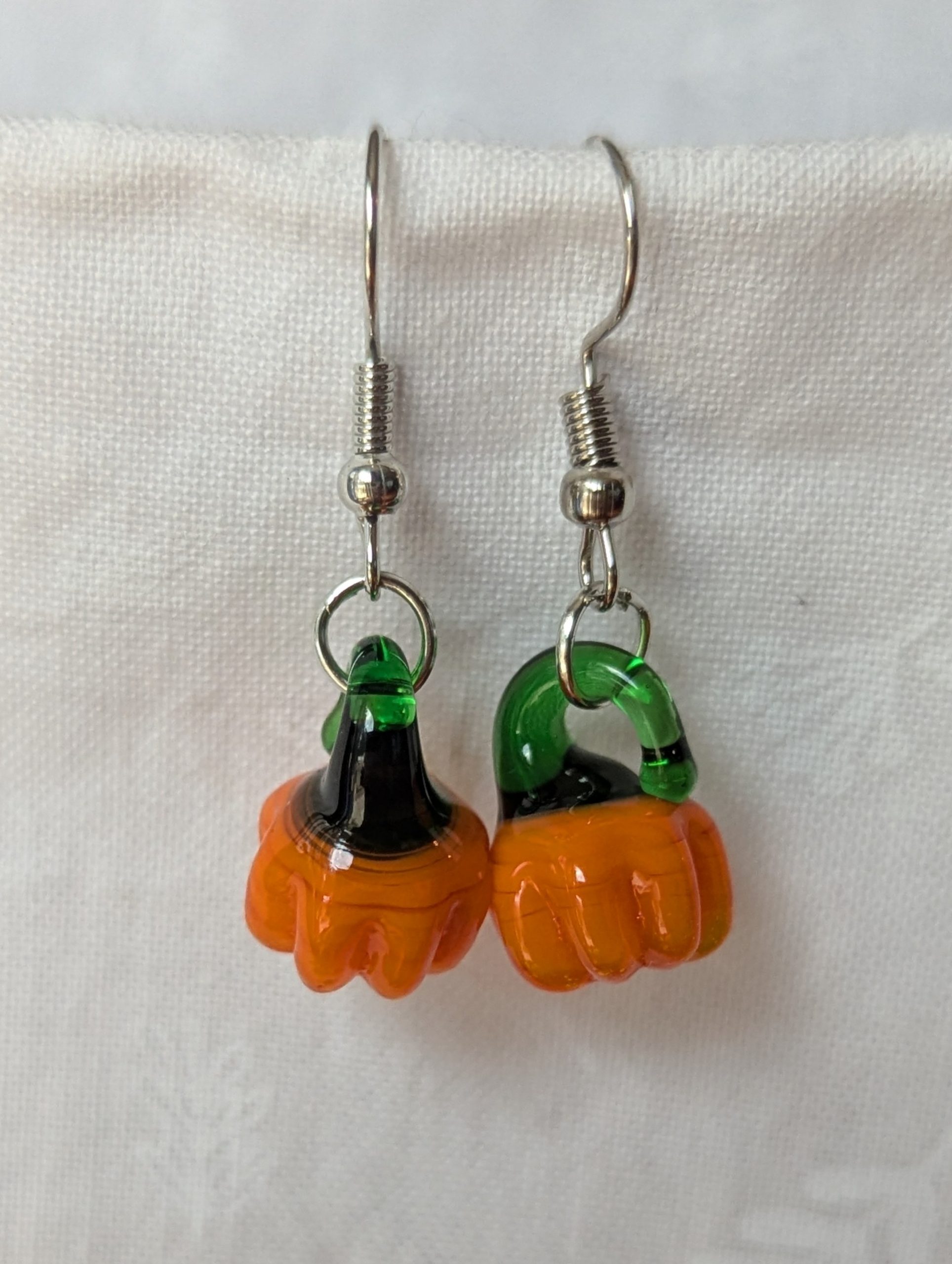 Handmade autumn pumpkin earrings with amber-orange glass pumpkin beads, green accents, and steel-colored findings.