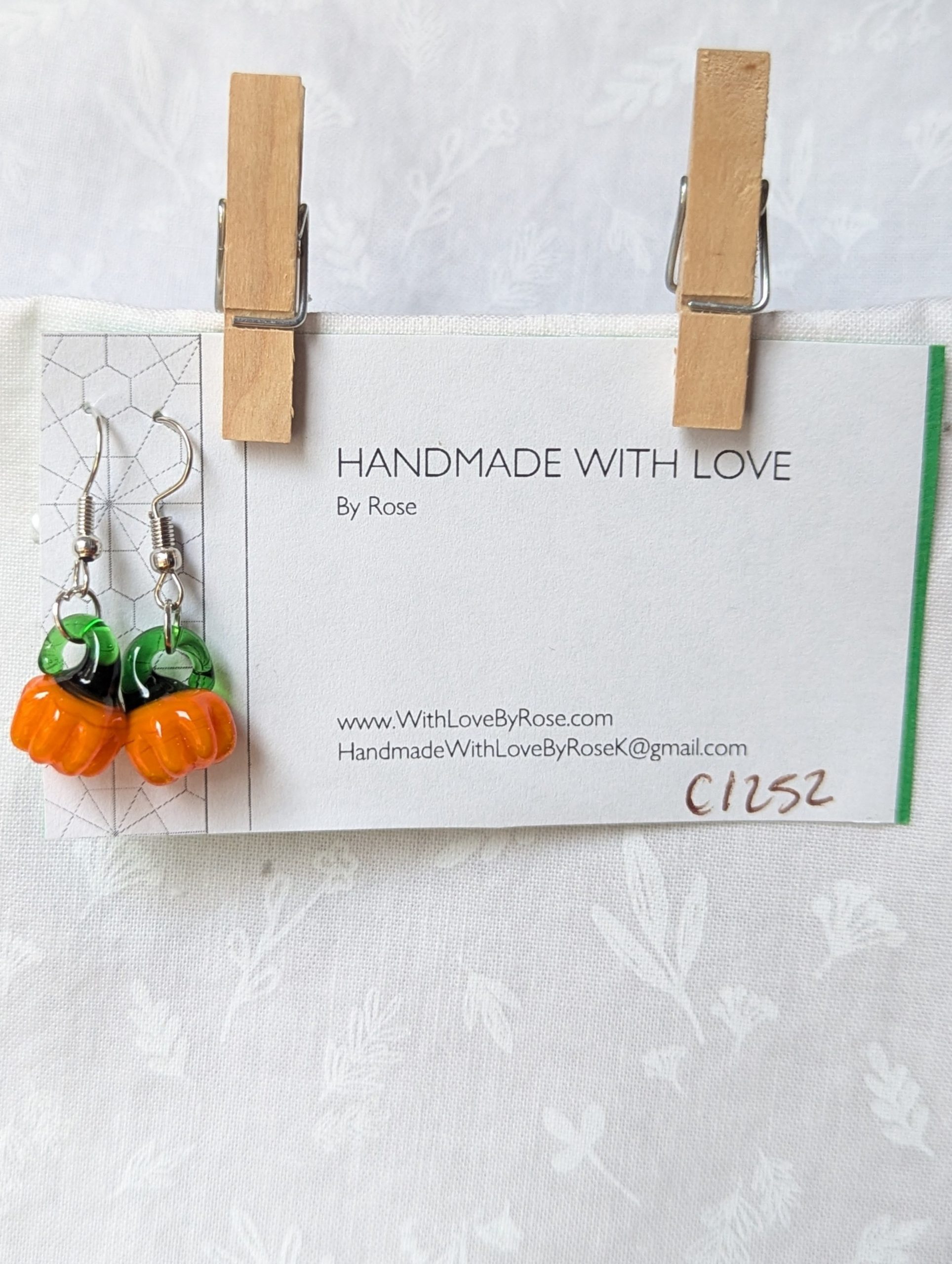 Handmade autumn pumpkin earrings with amber-orange glass pumpkin beads, green accents, and steel-colored findings.