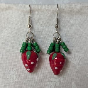 Handmade berry patch strawberry earrings with red and white polka-dotted glass strawberry beads, green seed bead accents, and steel-colored hooks.