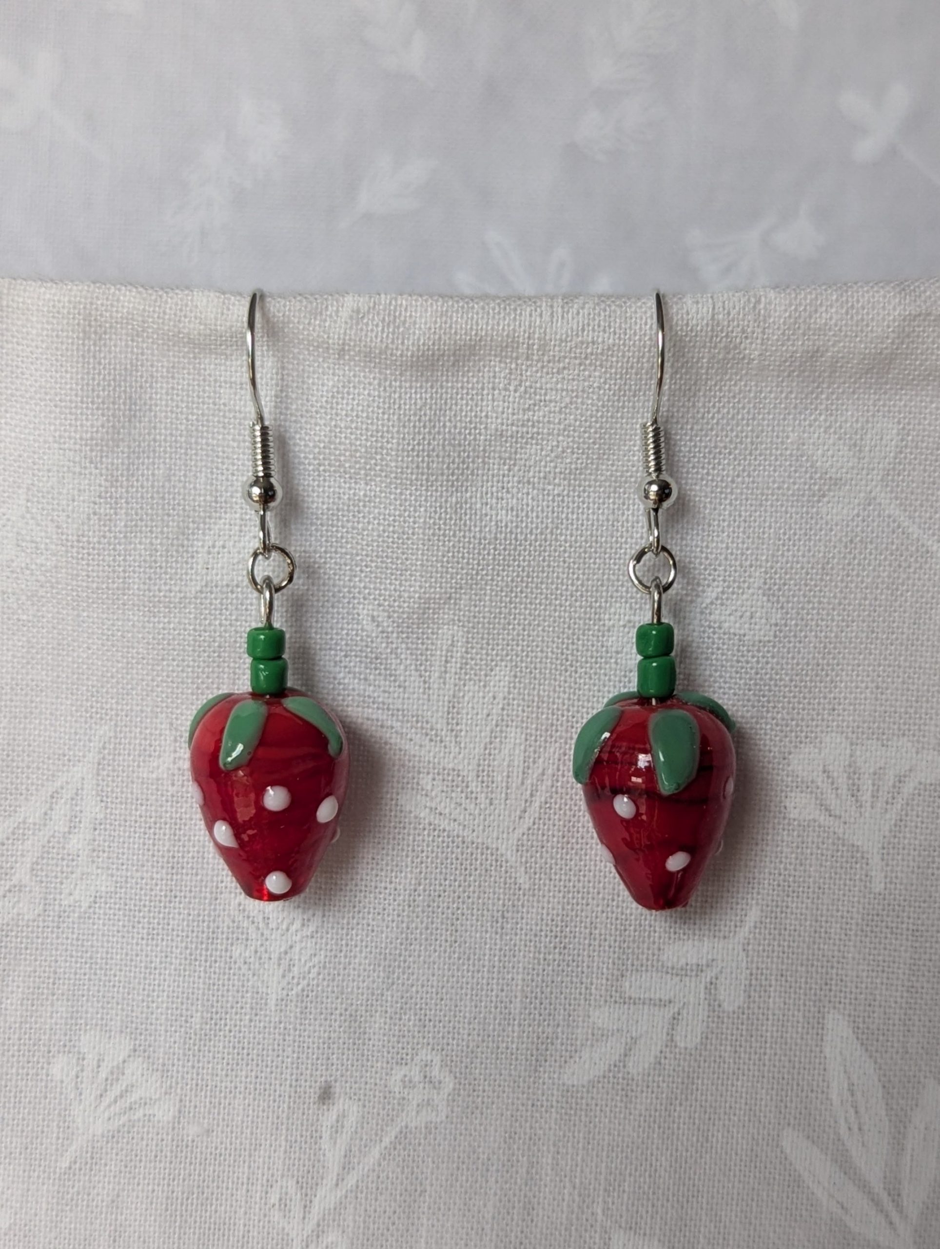 Handmade glass sweet strawberry earrings with red, green, and white details on steel hooks