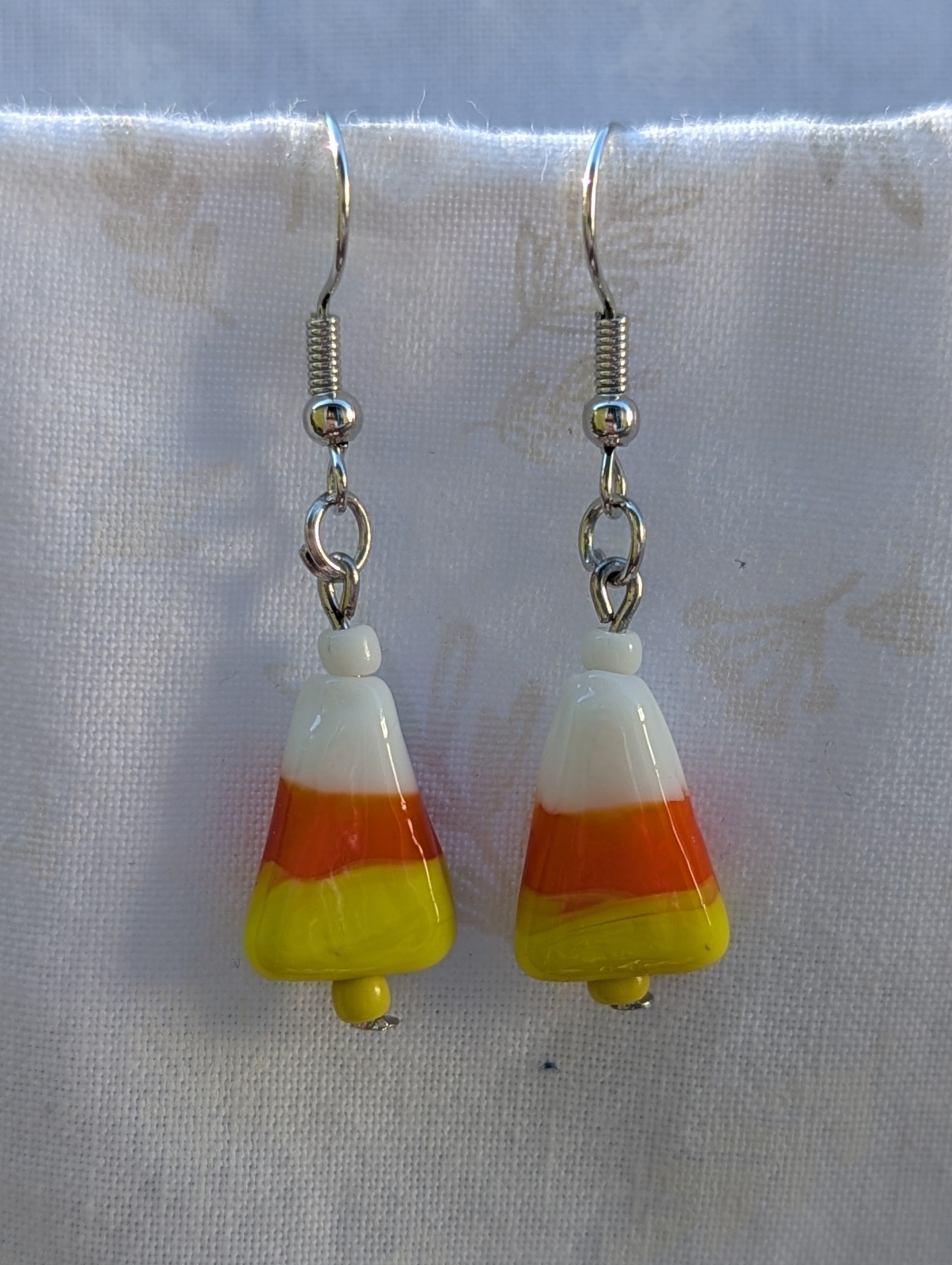 Candy corn glass Halloween earrings with yellow and white seed beads, sterling silver hooks, and silver jump rings for Halloween.