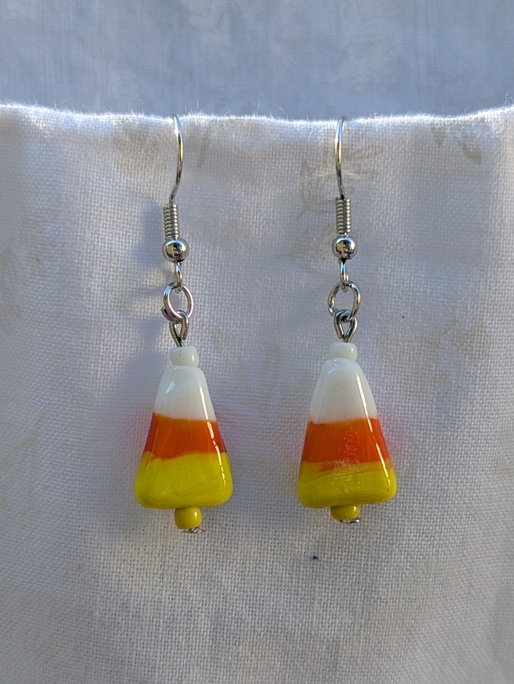 Candy corn glass Halloween earrings with yellow and white seed beads, sterling silver hooks, and silver jump rings for Halloween.