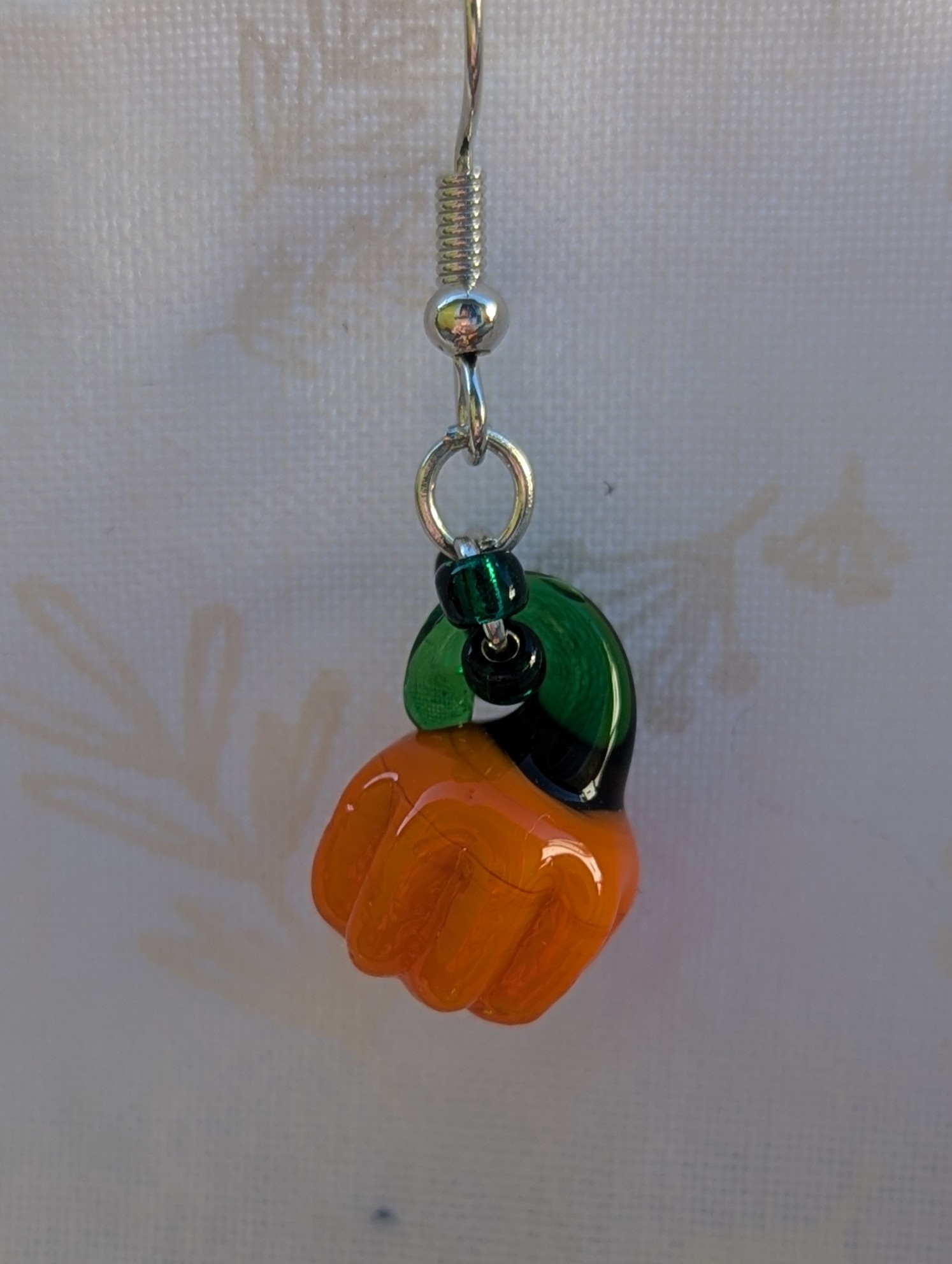Handmade Halloween pumpkin earrings with amber-orange glass pumpkin beads, green accents, and steel-colored findings.