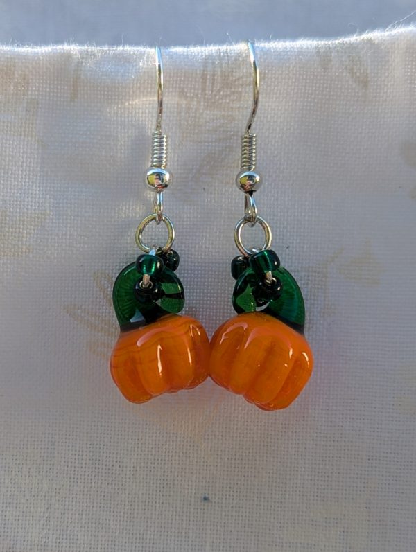 Handmade Halloween pumpkin earrings with amber-orange glass pumpkin beads, green accents, and steel-colored findings.