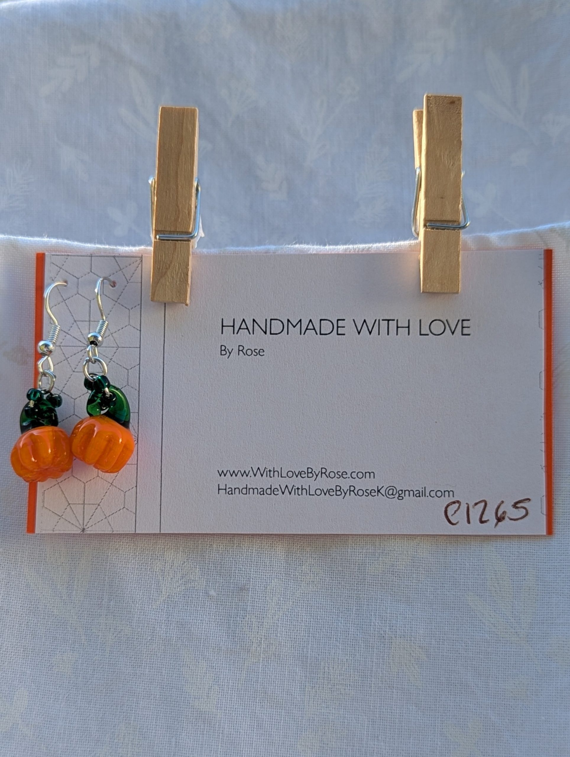 Handmade Halloween pumpkin earrings with amber-orange glass pumpkin beads, green accents, and steel-colored findings.