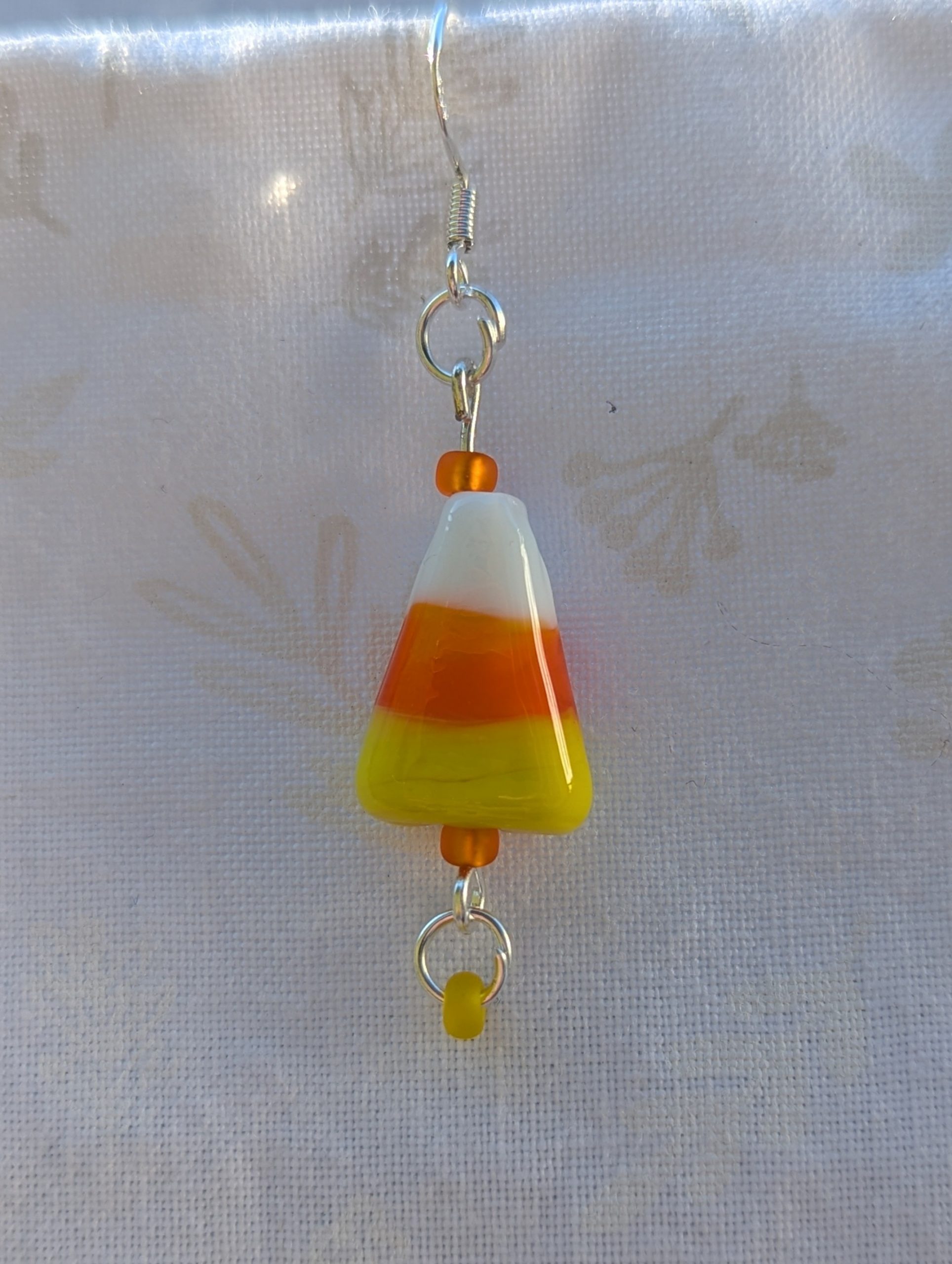 Candy corn glass Halloween earrings with yellow and orange seed beads, sterling silver hooks, and silver jump rings for Halloween.