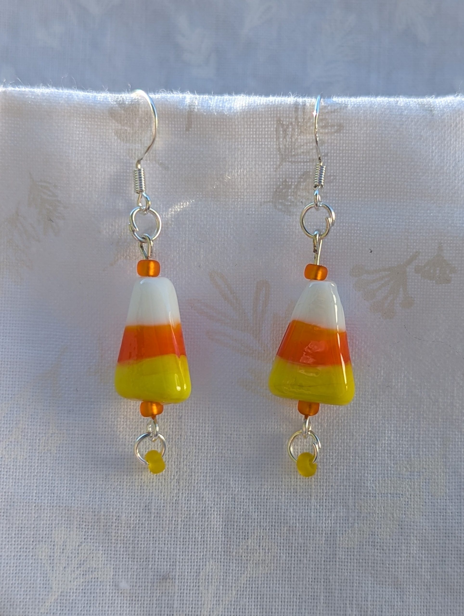 Candy corn glass Halloween earrings with yellow and orange seed beads, sterling silver hooks, and silver jump rings for Halloween.
