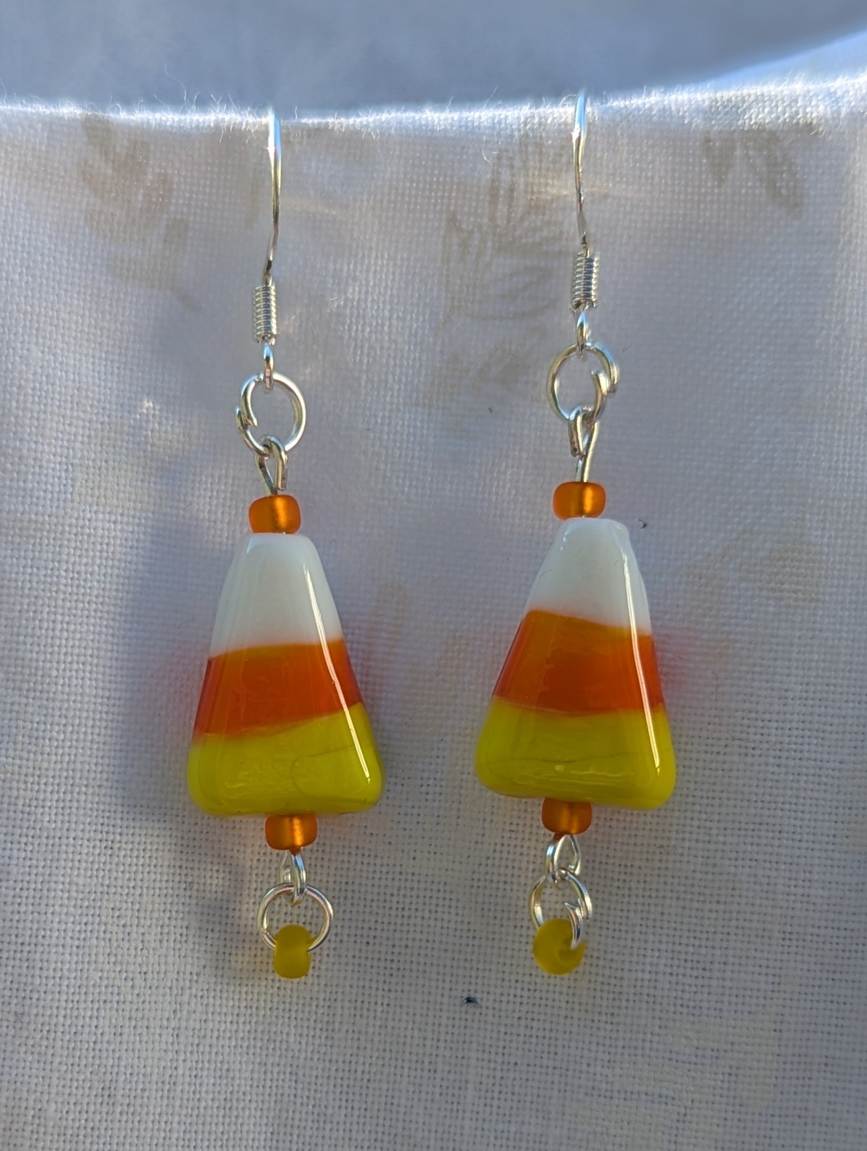 Candy corn glass Halloween earrings with yellow and orange seed beads, sterling silver hooks, and silver jump rings for Halloween.