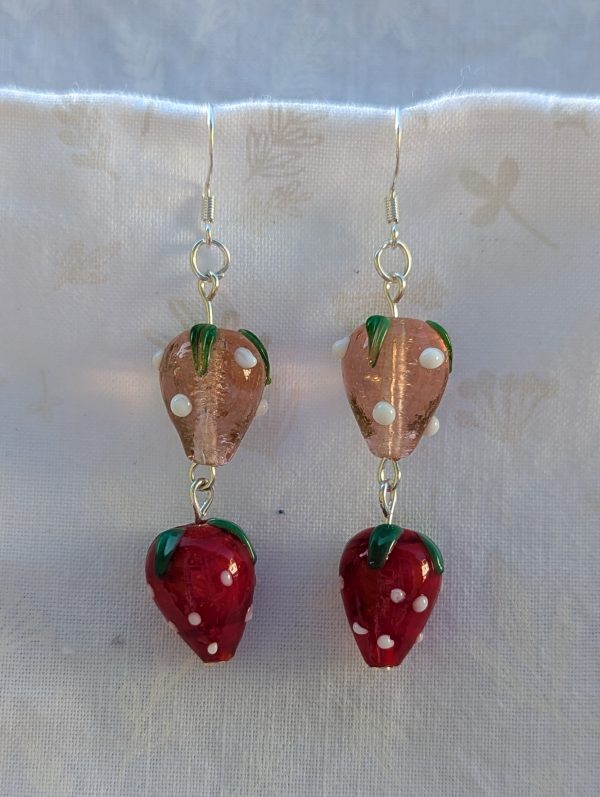 Handmade glass strawberry patch earrings with red, pale pink, green, and white details on sterling silver hooks.