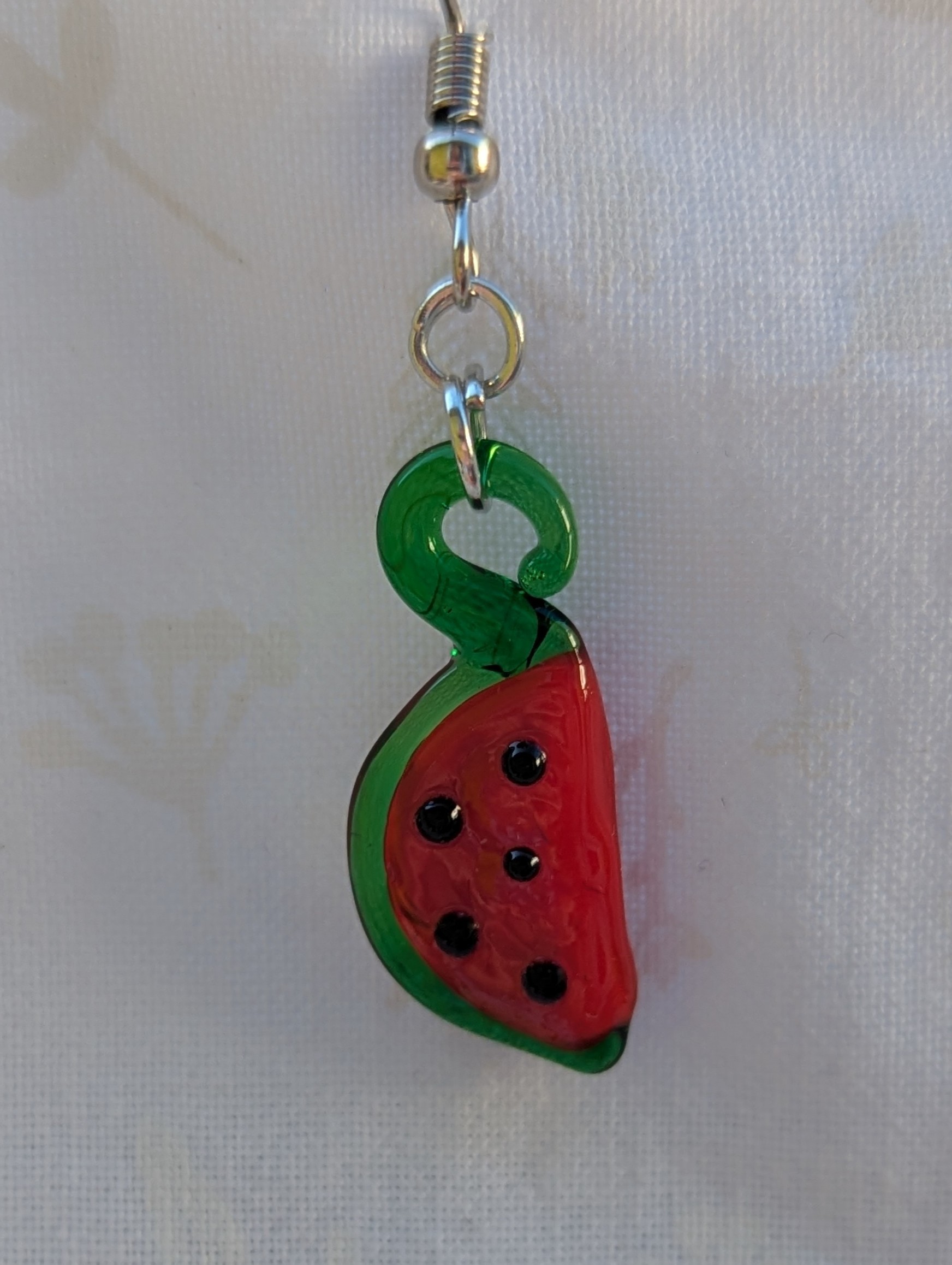 Handmade glass watermelon slice earrings with pink-red centers, green rinds, and sterling silver hooks.