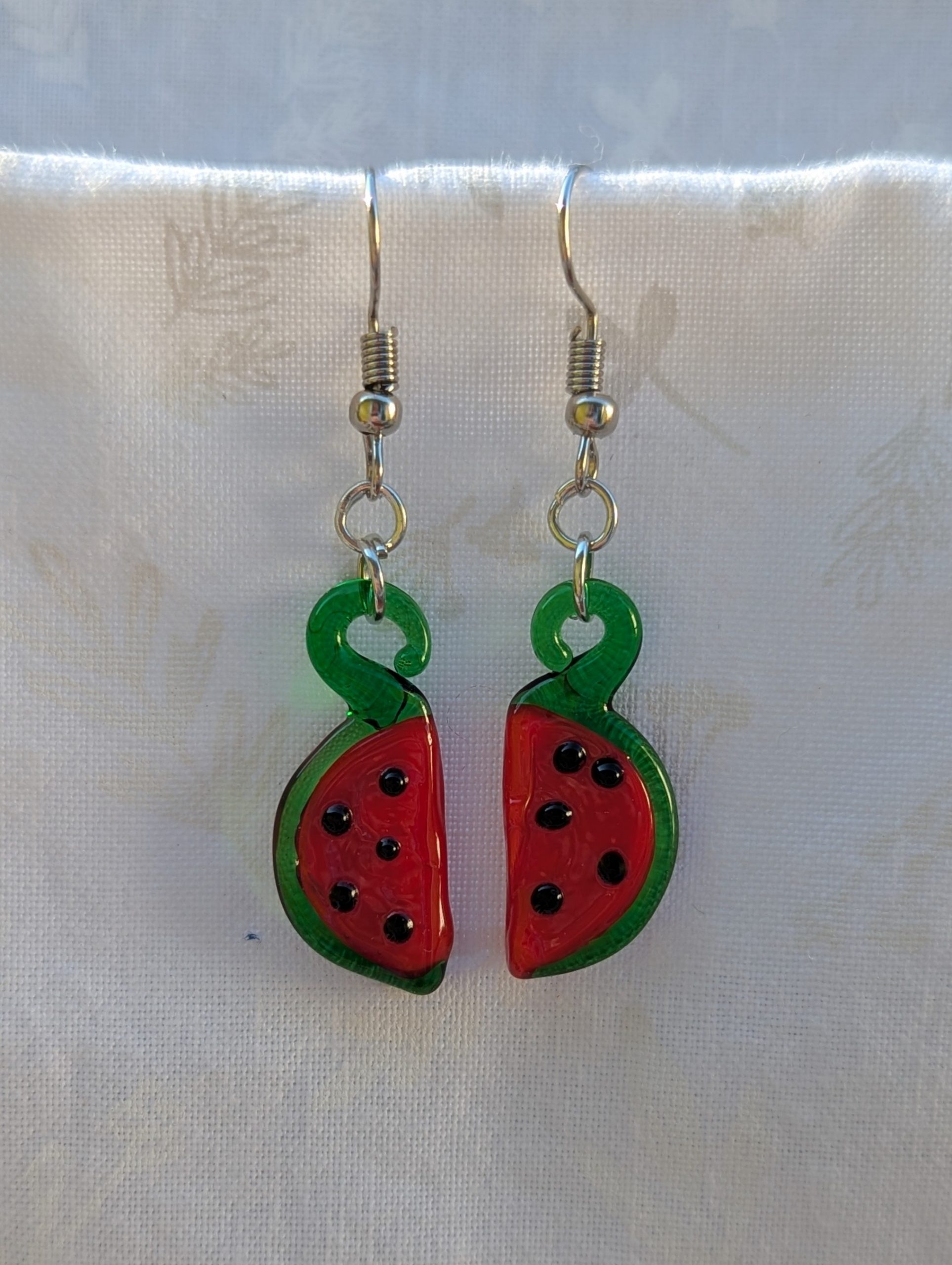 Handmade glass watermelon slice earrings with pink-red centers, green rinds, and sterling silver hooks.
