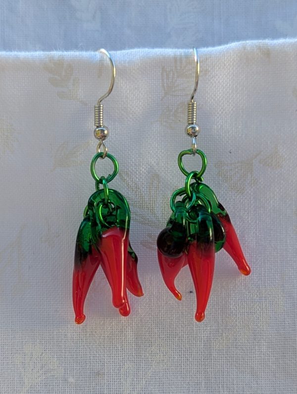 Handmade chili pepper earrings with four red glass peppers linked by green aluminum rings and hung from steel French hooks.