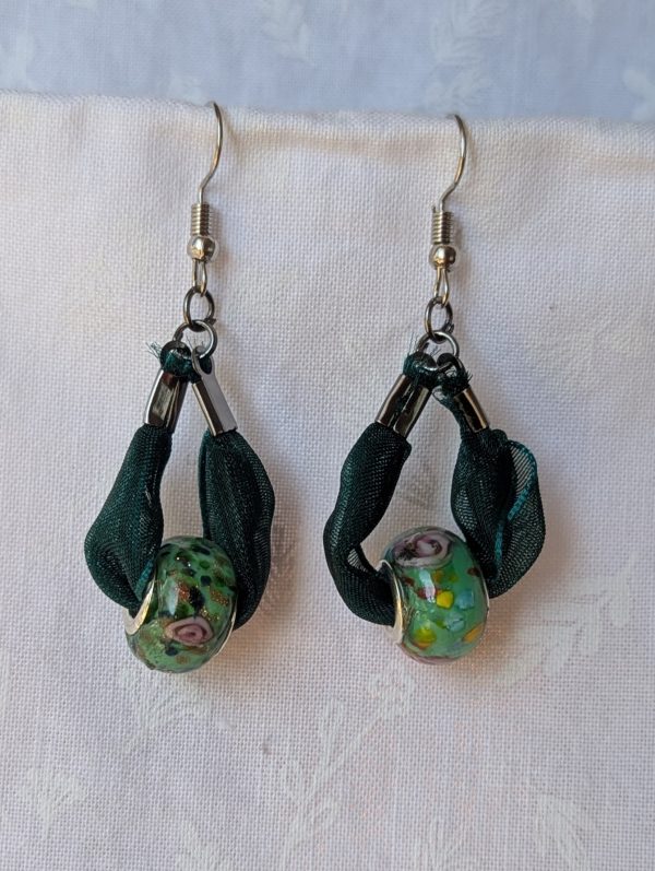 Handmade green ribbon earrings featuring floral glass beads with tungsten metal accents and steel hooks.