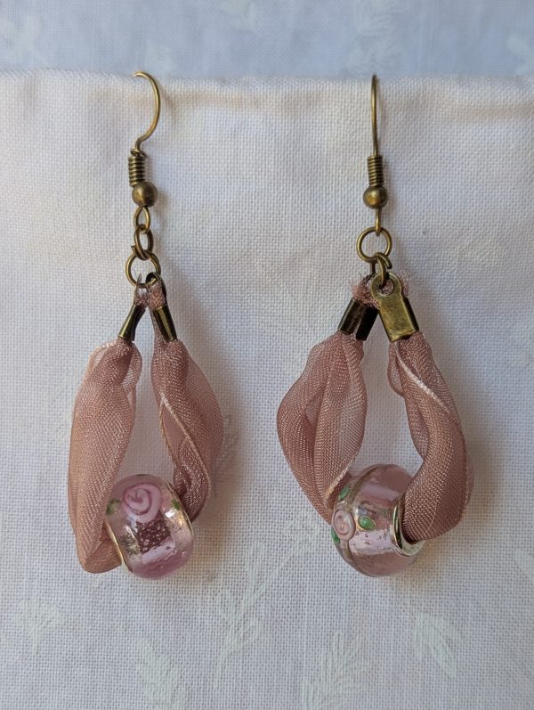 Handmade pale pink ribbon earrings featuring floral glass beads with bronze metal accents and steel hooks.