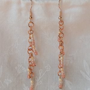 Handmade blush cream beaded earrings featuring pale pink and cream glass beads in four shades, linked with copper jump rings and rose-gold hooks.