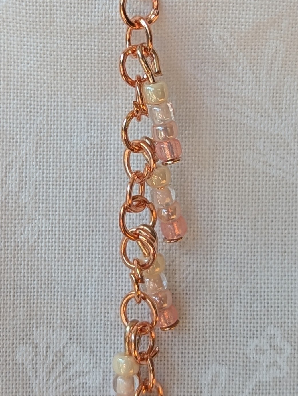 Handmade blush cream beaded earrings featuring pale pink and cream glass beads in four shades, linked with copper jump rings and rose-gold hooks.