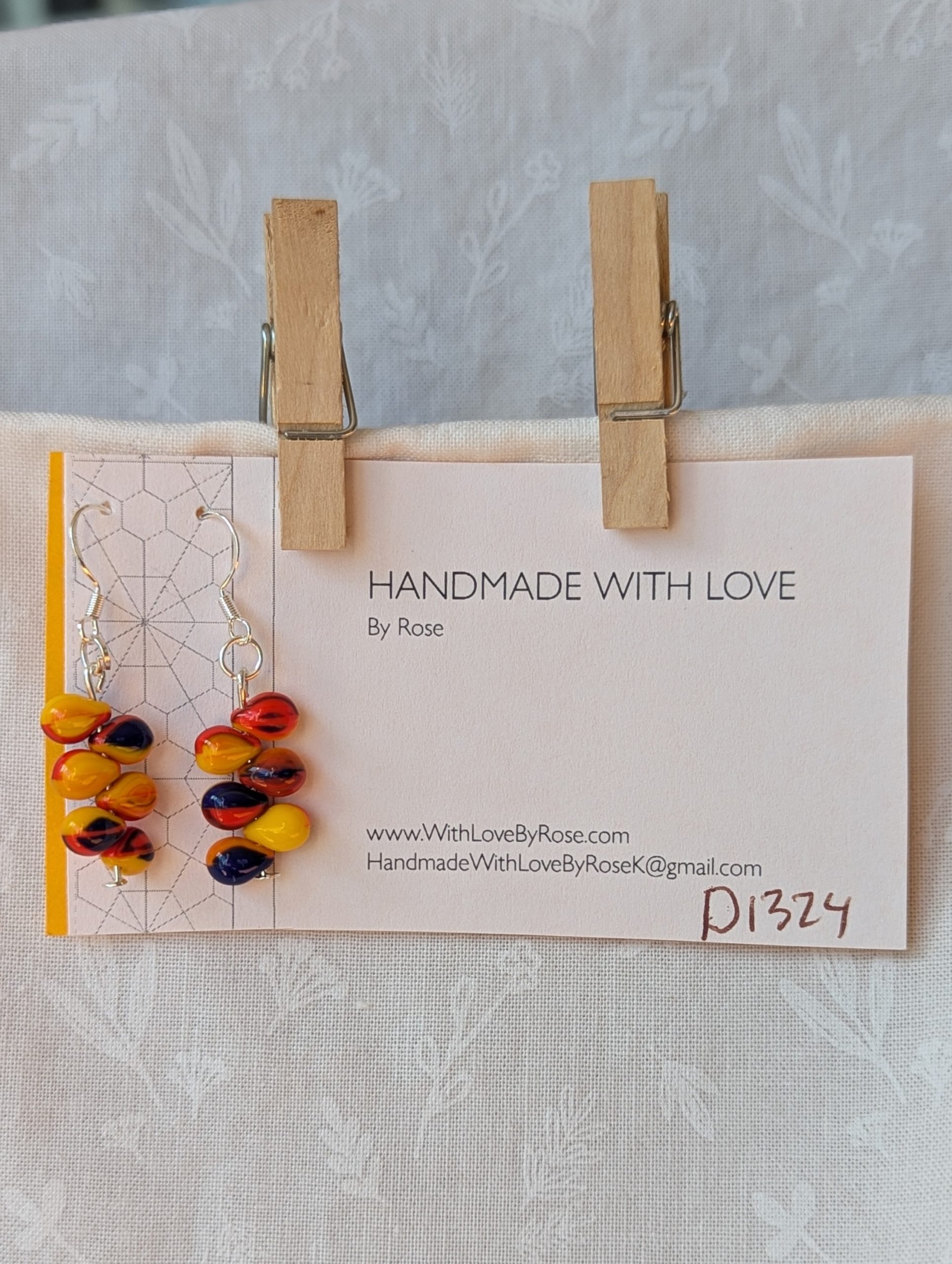 Handmade fireburst glass bead earrings featuring yellow, red, and blue teardrop beads on silver pins with sterling silver hooks.