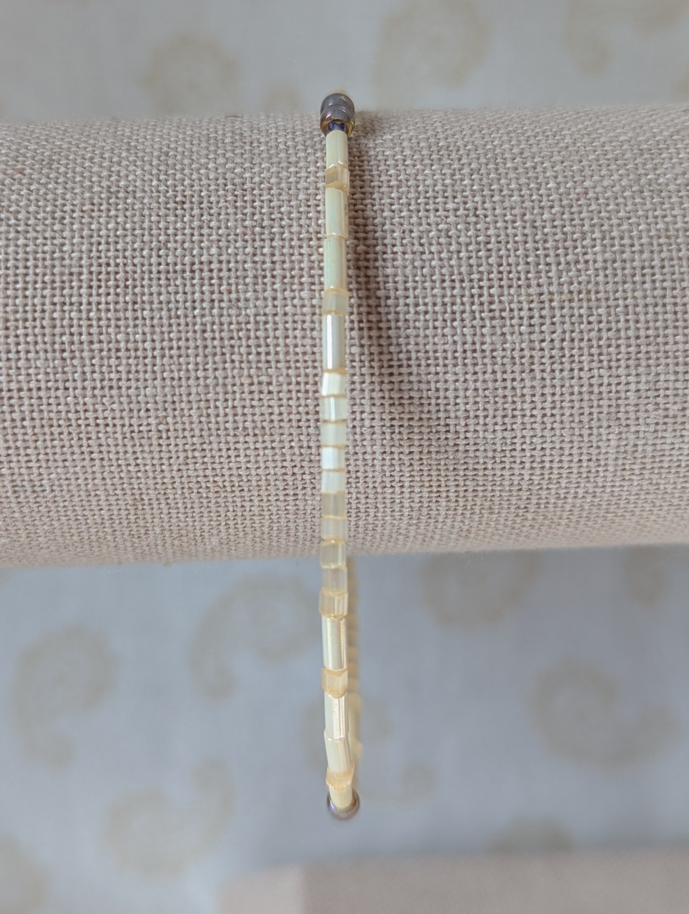 Handmade bracelet with short pearl-cream beads, long ivory-cream beads, and lavender-lined gray beads on silver-plated memory wire with a silver lobster clasp.