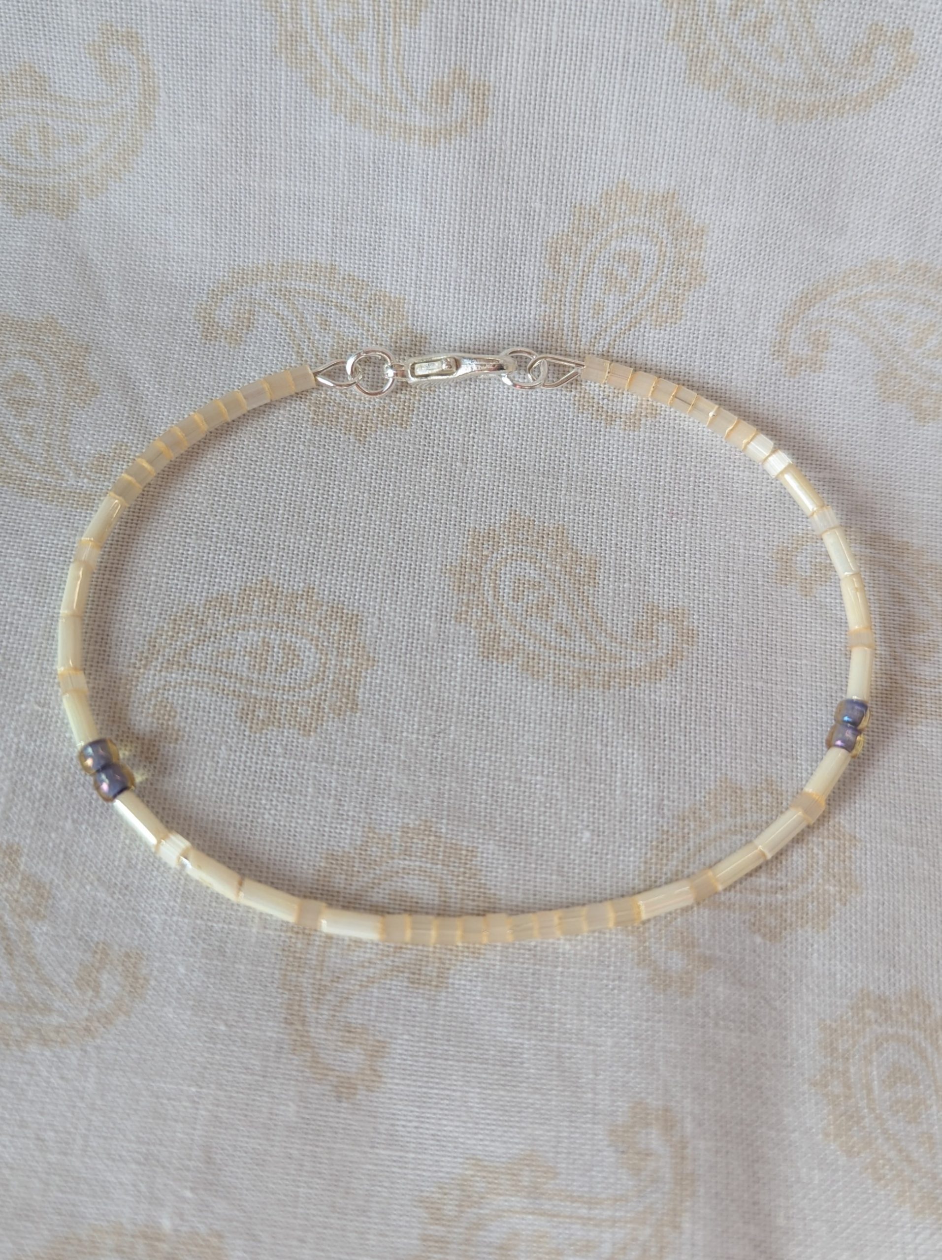 Handmade bracelet with short pearl-cream beads, long ivory-cream beads, and lavender-lined gray beads on silver-plated memory wire with a silver lobster clasp.