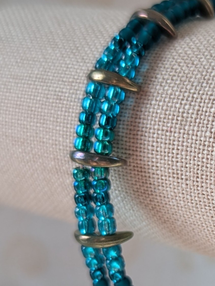 Handmade teal crescent bracelet with layered teal seed beads, metallic crescent beads, and a silver lobster clasp.