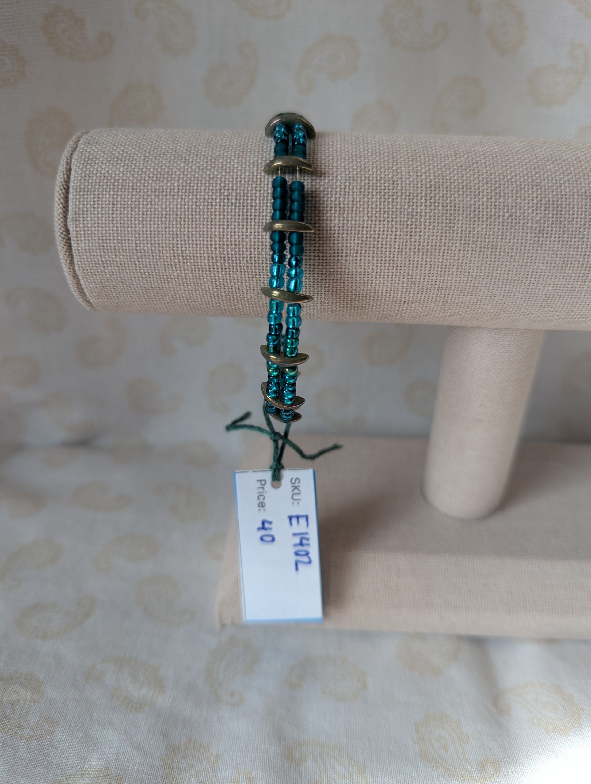 Handmade teal crescent bracelet with layered teal seed beads, metallic crescent beads, and a silver lobster clasp.