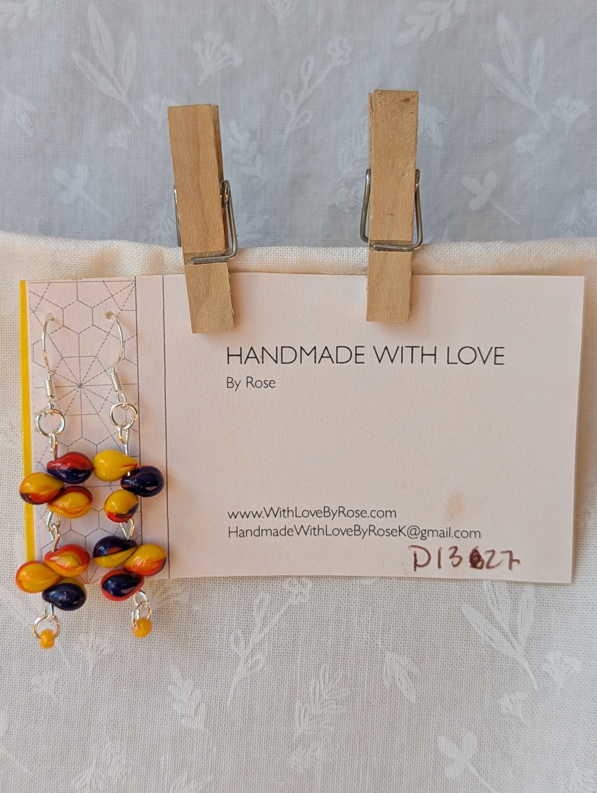 Handmade carnival-themed earrings with cascading yellow, red, and blue glass teardrop beads and a small yellow seed bead on sterling silver hooks.