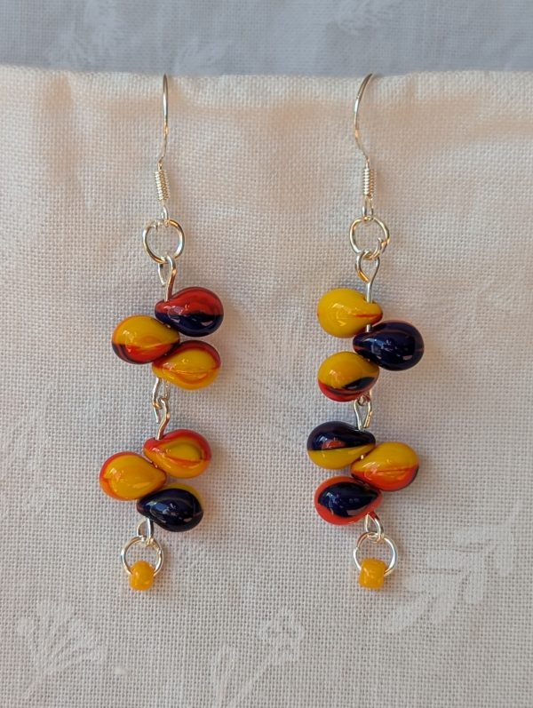 Handmade carnival-themed earrings with cascading yellow, red, and blue glass teardrop beads and a small yellow seed bead on sterling silver hooks.