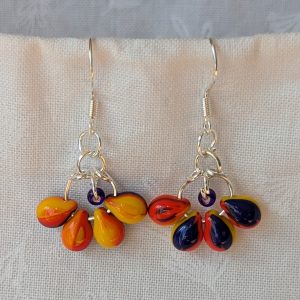 Handmade carnival glass teardrop earrings with yellow, red, and blue beads plus a blue seed bead on sterling silver hooks.