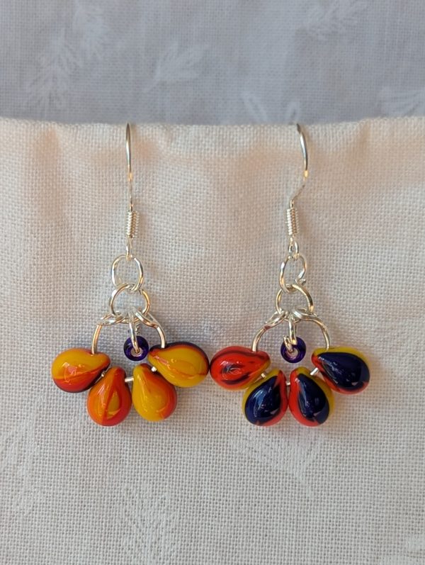 Handmade carnival glass teardrop earrings with yellow, red, and blue beads plus a blue seed bead on sterling silver hooks.