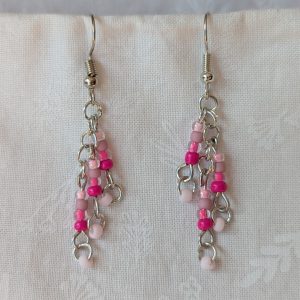 Handmade pink beaded earrings featuring five shades of pink glass beads on steel jump rings and hooks.
