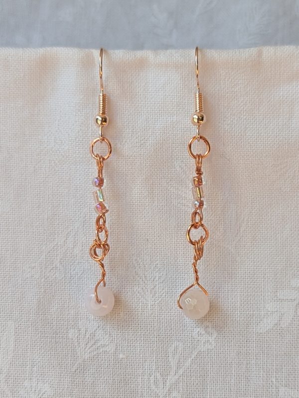 Handmade blush moonlight earrings with white Czech cut beads and pink seed beads wrapped in copper wire on rose-gold hooks.