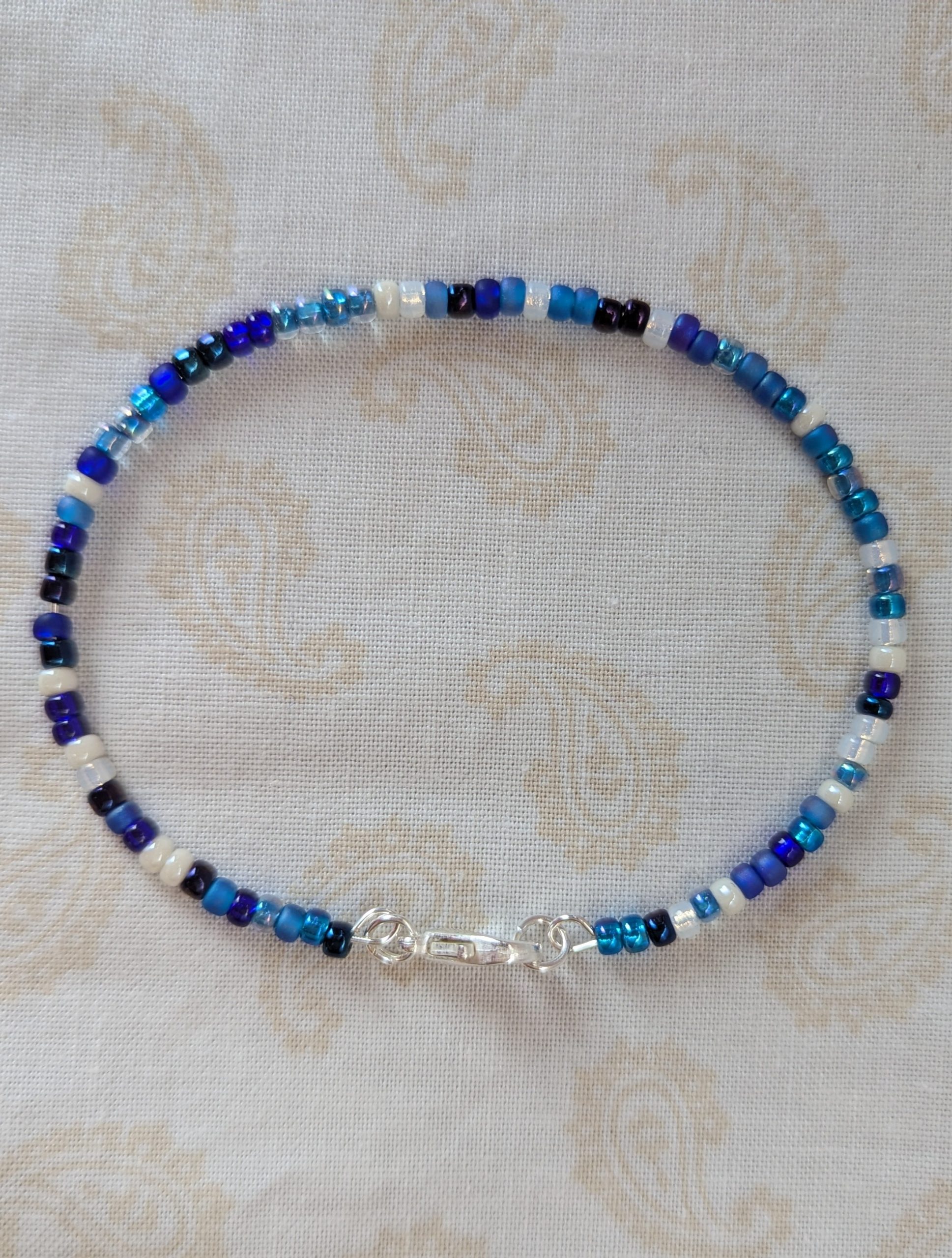 Handmade blue and white bracelet with mixed blue glass beads, white accent beads, and a silver lobster clasp.