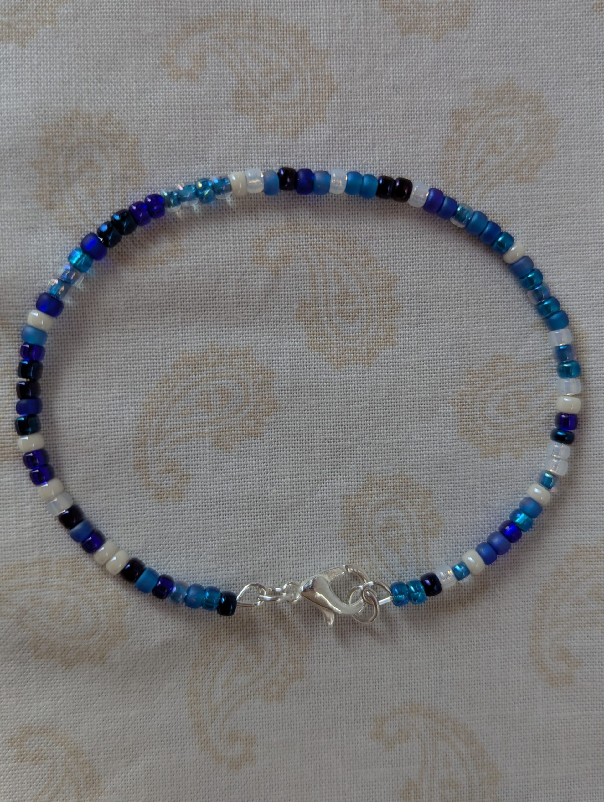 Handmade blue and white bracelet with mixed blue glass beads, white accent beads, and a silver lobster clasp.