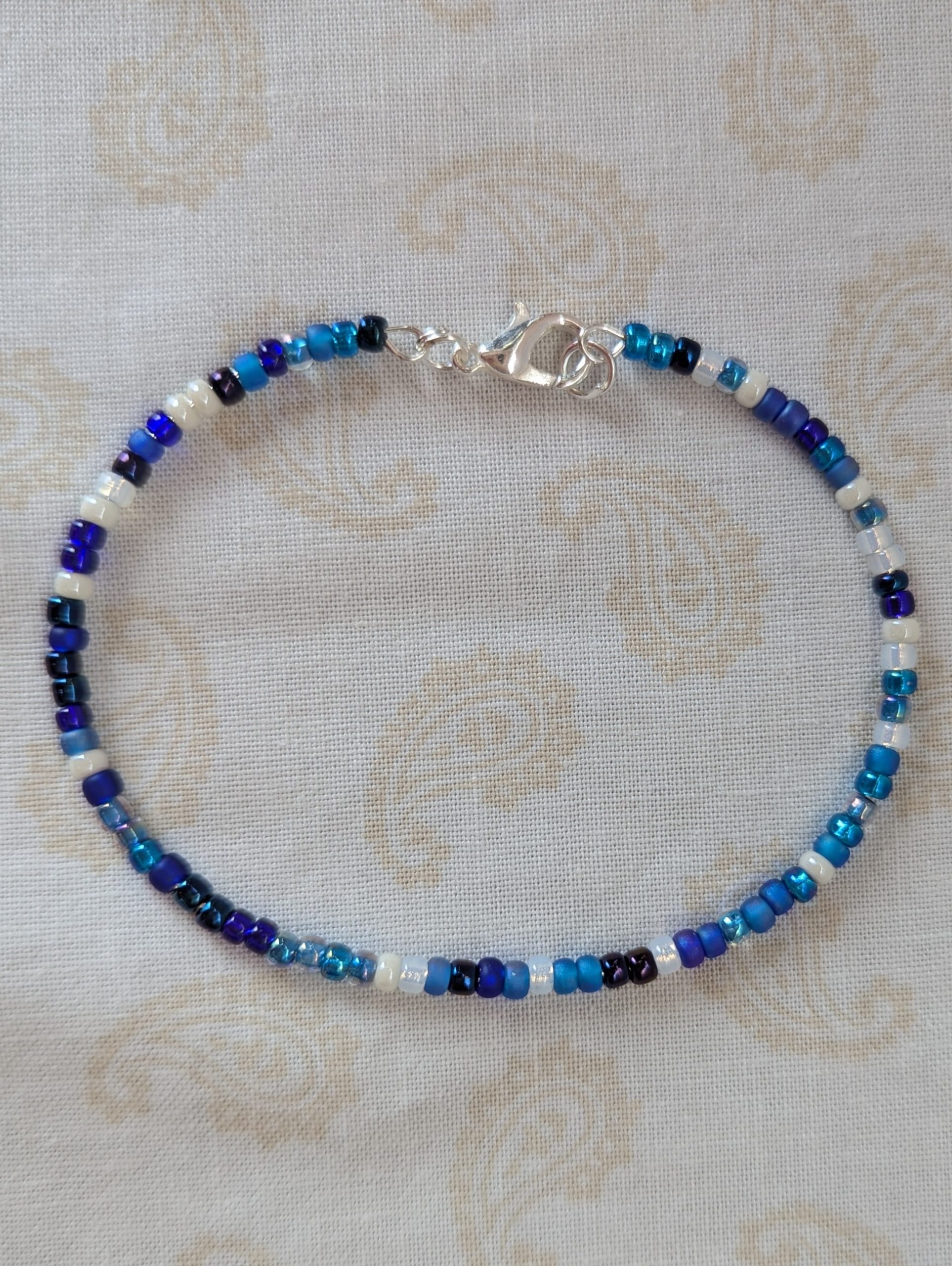 Handmade blue and white bracelet with mixed blue glass beads, white accent beads, and a silver lobster clasp.