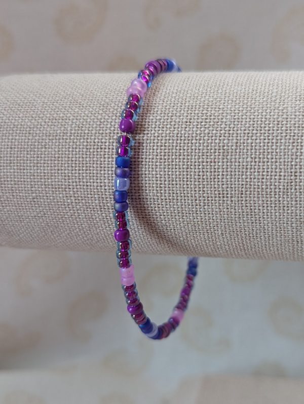 Purple blue beaded bracelet with memory wire featuring amethyst, indigo, and periwinkle glass beads in mixed textures and a silver lobster clasp