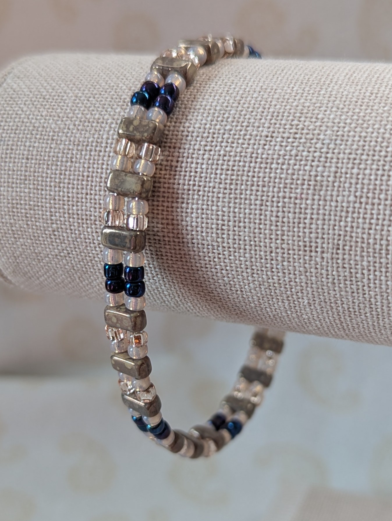 Double-strand memory wire bracelet with pale pink, iridescent blue seed beads and taupe rectangular stone beads, finished with a silver lobster clasp.