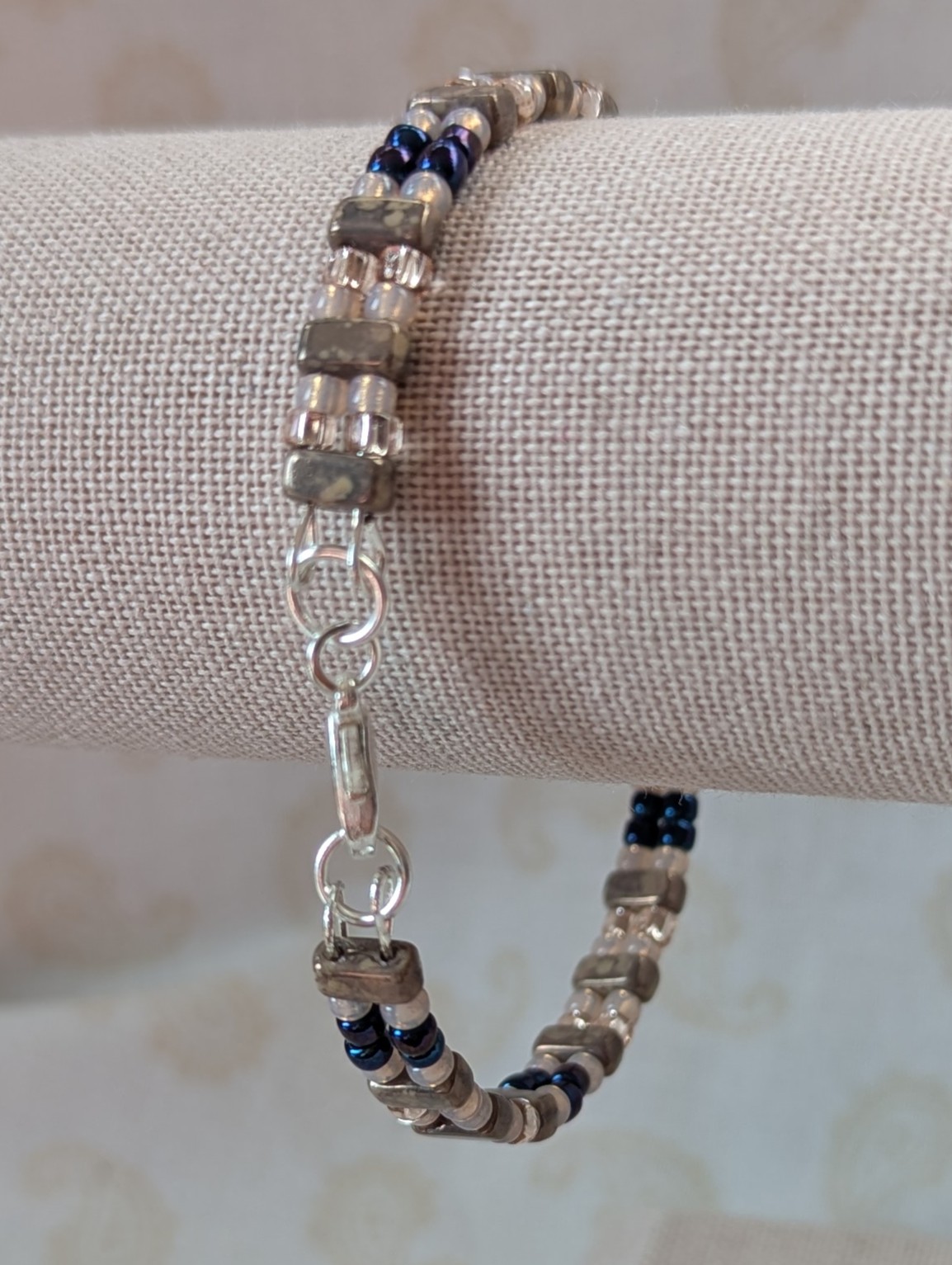 Double-strand memory wire bracelet with pale pink, iridescent blue seed beads and taupe rectangular stone beads, finished with a silver lobster clasp.