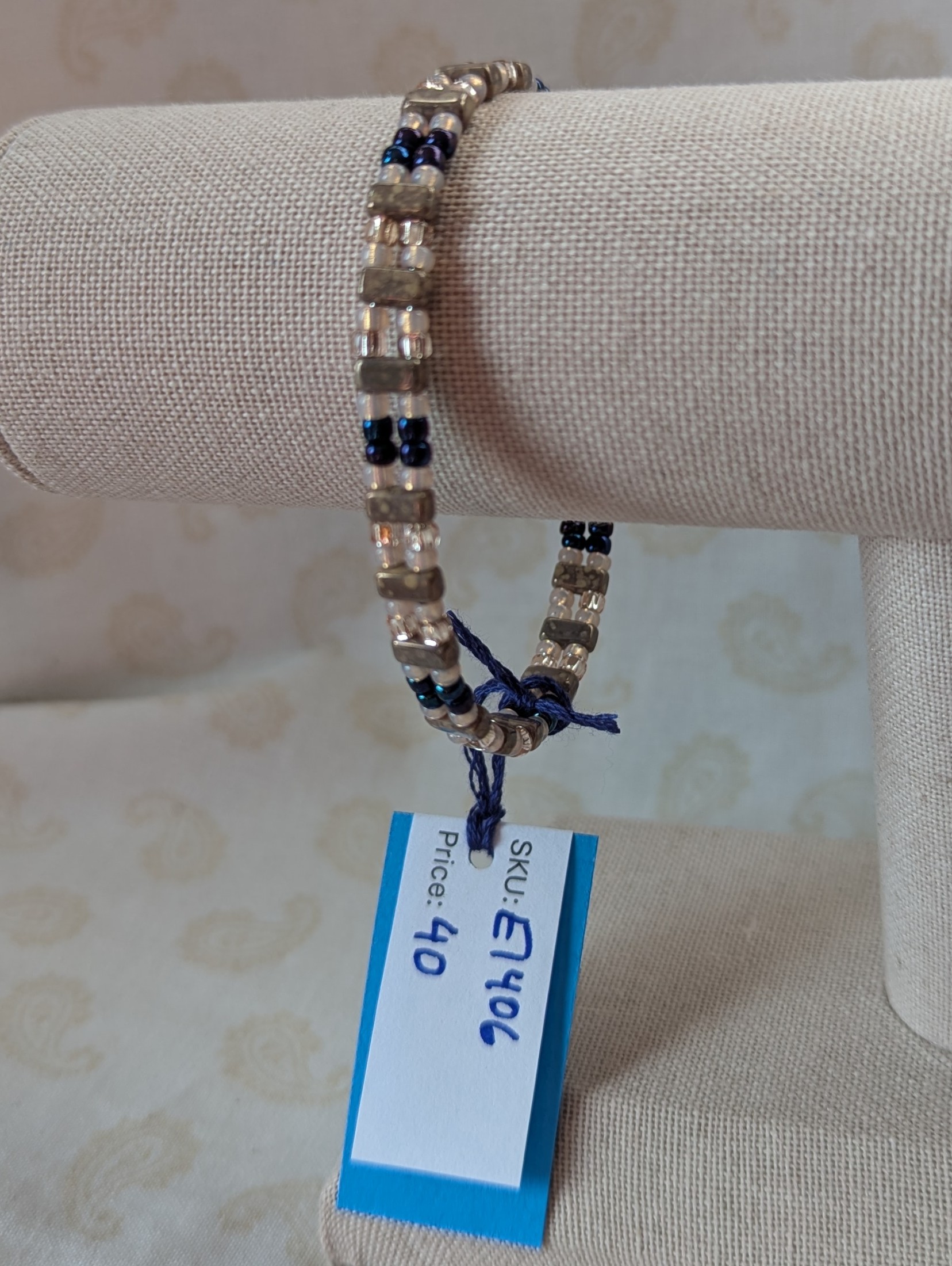 Double-strand memory wire bracelet with pale pink, iridescent blue seed beads and taupe rectangular stone beads, finished with a silver lobster clasp.