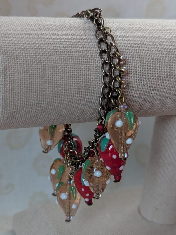 Bronze chain bracelet with red and pale pink strawberry lampwork beads accented by small matching seed beads and a bronze lobster clasp.